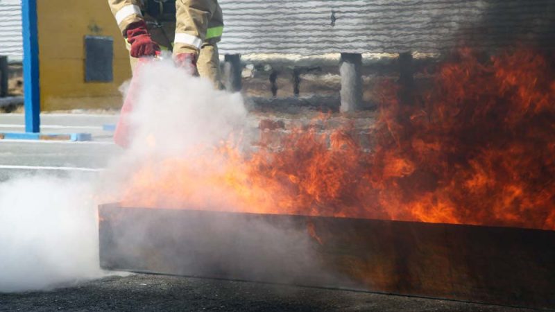 Extinguishing a major fire. A professional fireman in a special suit extinguishes an open fire with a fire extinguisher. Training firefighters for extinguishing fires